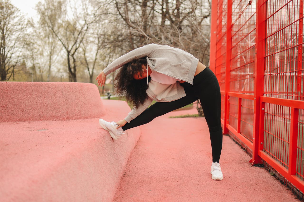 Woman stretching outdoors against a bright red structure, promoting fitness and wellness.